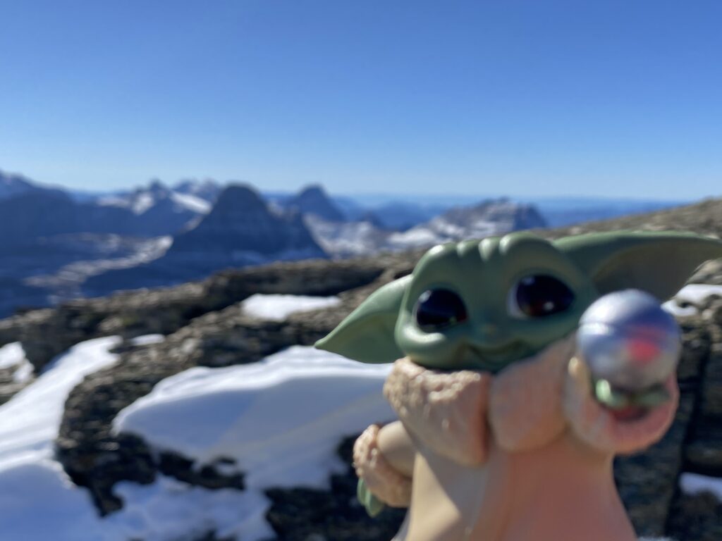 Baby Yoda toy staged on a mountain top